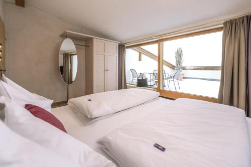 a bedroom with two beds and a large window at Hotel Acherl in Achenkirch