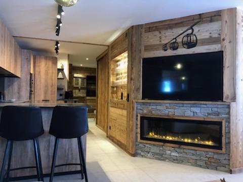 - un salon avec une cheminée, une télévision et des tabourets dans l'établissement La Loge Des Chats, à La Toussuire