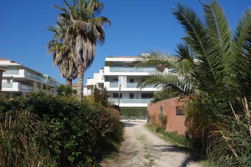 eine unbefestigte Straße mit Palmen und einem weißen Gebäude in der Unterkunft Jardin d'Eden in La Ciotat
