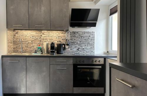 a kitchen with stainless steel appliances and a stone wall at RIOs Apartments in Scharnitz