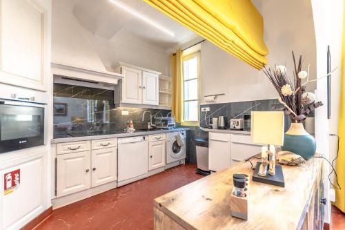 une grande cuisine avec des placards blancs et une table en bois dans l'établissement Le Seillon l Perfect Location l Shellter Rentals, à Saint-Tropez