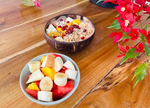 a bowl of fruit and a bowl of cereal on a table at Utopia Varkala - Boutique stay in Odayam rice fields in Varkala