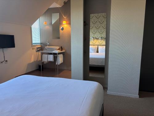 a bedroom with a bed and a sink and a mirror at Droste's Herberg in Tubbergen