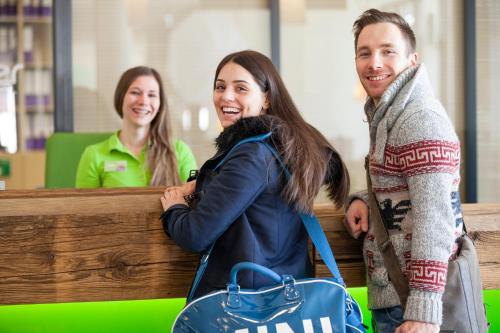 a man and two women standing next to a bench at Explorer Hotel Neuschwanstein in Nesselwang