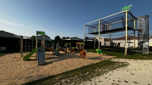 a playground with a glass building in the background at Mobilhome trigano au Camping Les Charmettes emplacement calme in Les Mathes