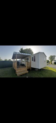 une petite maison avec un porche et une terrasse dans l'établissement Mobilhome trigano au Camping Les Charmettes emplacement calme, aux Mathes
