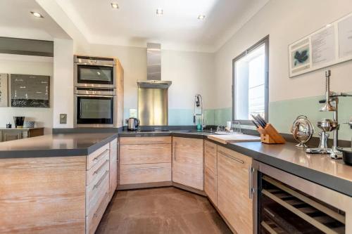 une grande cuisine avec des placards en bois et des comptoirs noirs dans l'établissement Loft Jasmin l Terrace & Space l Shellter Rentals, à Saint-Tropez