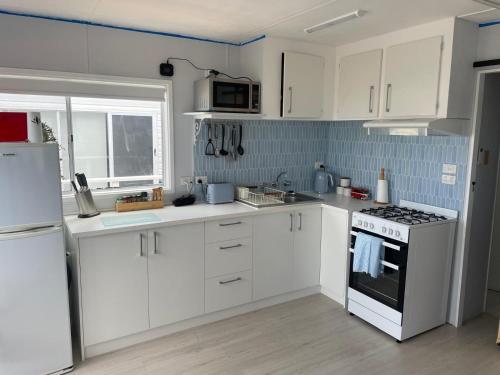 a kitchen with white cabinets and a stove top oven at Cozy Cabin by the beach in Apollo Bay
