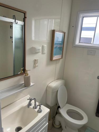 a white bathroom with a toilet and a sink at Cozy Cabin by the beach in Apollo Bay