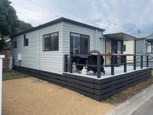 a tiny house with a porch and a deck at Cozy Cabin by the beach in Apollo Bay