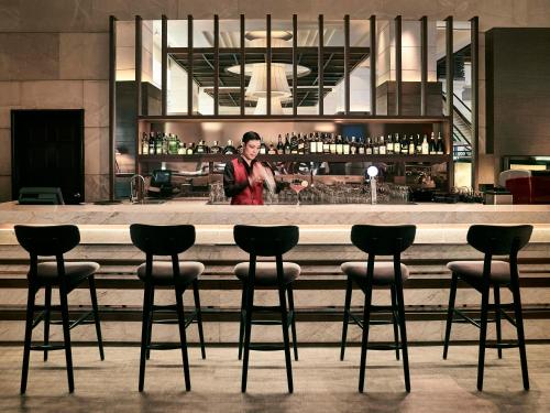 a woman standing behind a bar in a building at Pan Pacific Hanoi in Hanoi