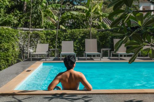 a man sitting in a swimming pool at Seaside Naithon Phuket - Newly Opened in Nai Thon Beach