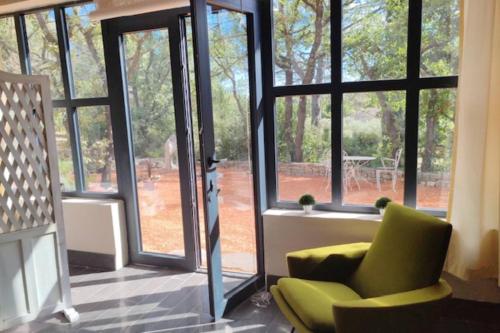 - un salon avec une chaise verte et de grandes fenêtres dans l'établissement The Rose Garden - Pernes-les-Fontaines, à Pernes-les-Fontaines