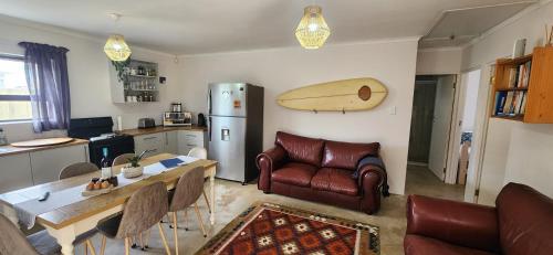 eine Küche mit einem Tisch und einem Surfbrett an der Wand in der Unterkunft The Beach Cottage Betty's Bay in Bettyʼs Bay