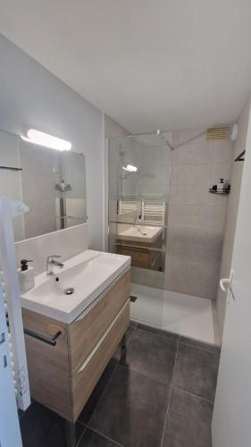 une salle de bain avec un lavabo blanc et une douche dans l'établissement Appartement T2 avec Balcon, Parking Privée à 2min de la plage, Rue Piétonne, à Saint-Jean-de-Monts