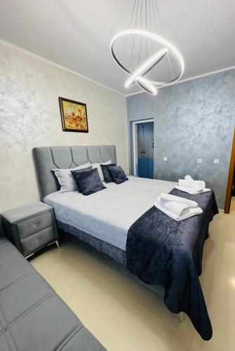 a bedroom with a king sized bed and a chandelier at Къща за гости Аси in Dospat