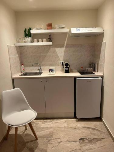 a small kitchen with a sink and a white chair at Tolo Blue Bay in Tolo