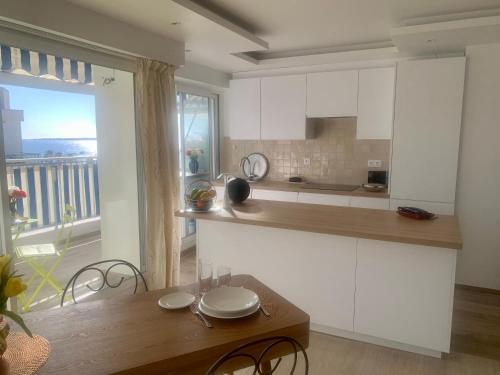 une cuisine avec des placards blancs et une table en bois avec des chaises dans l'établissement Aperçu mer, à Vallauris
