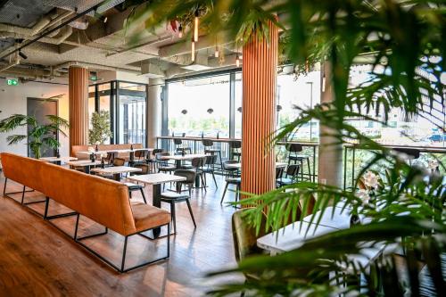 a restaurant with tables and chairs and plants at Fletcher Hotel Rotterdam-Airport in Rotterdam