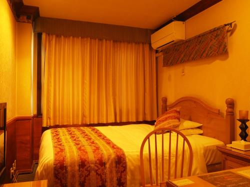 a bedroom with a bed and a window with curtains at Hotel Gasthof in Kagoshima