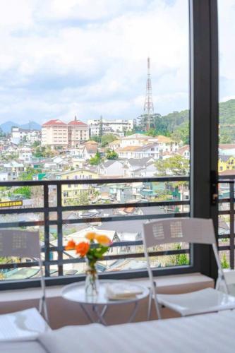 a table with a vase of flowers and a view of a city at Ami Villa Dalat in Da Lat