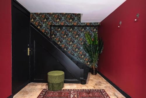a staircase with a green stool next to a red wall at Suite avec jacuzzi - Le Boudoir de la Loire in Chalonnes-sur-Loire