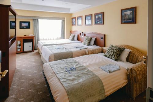 a hotel room with three beds and a couch at Boston Plaza Kusatsu Biwa Lake - Vacation STAY 15463v in Kusatsu