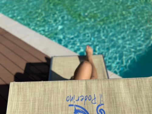 a person sitting on a chair next to a swimming pool at Residence Talamone Il Poderino in Talamone