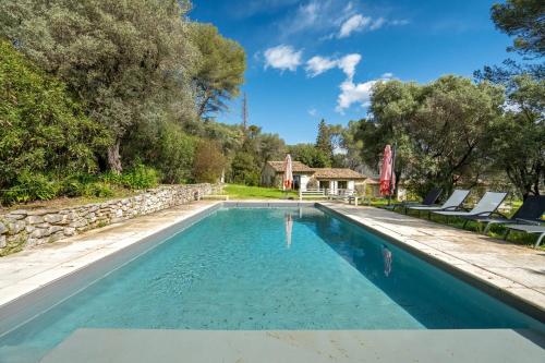 une piscine avec des chaises et une maison dans l'établissement Villa La Campanette, à La Colle-sur-Loup