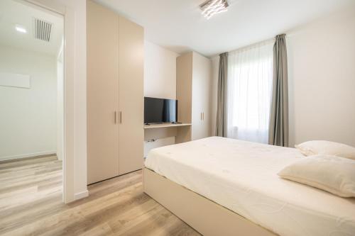 ein weißes Schlafzimmer mit einem Bett und einem Fernseher in der Unterkunft Wave Island A18 in Lido di Jesolo