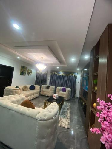 a living room with white couches and a tv at Luxury 2 Bedroom Apartment in Magodo