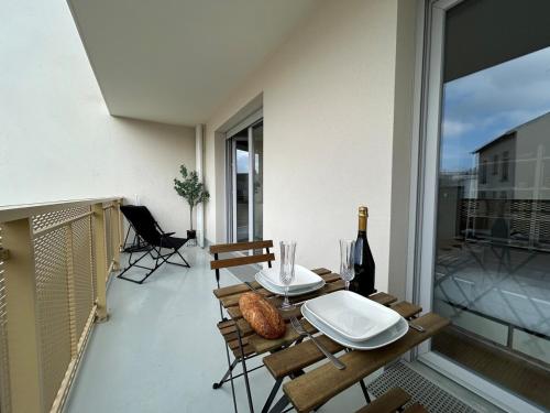 a table on a balcony with a bottle of wine at Bleuets studio cosy neuf terrasse proche centre in Reims