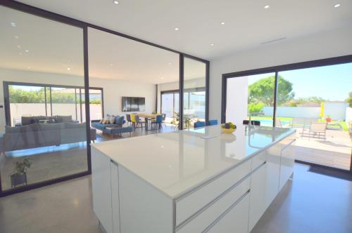 une cuisine avec des armoires blanches et un salon dans l'établissement Villa Noam Haut Standing 220m2, à Beauvoisin