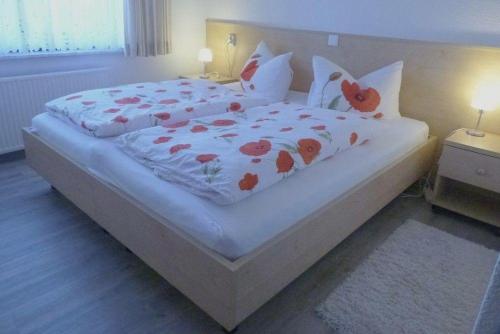 a large white bed with red flowers on it at Seerose in Wittdün