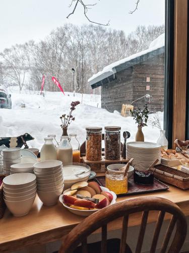 a table with bowls and plates of food on it at Country Inn Milky House in Niseko
