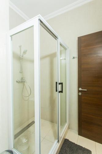 a glass shower stall with a wooden door in a bathroom at Accra Luxury Apartments at Avant Garde in Accra