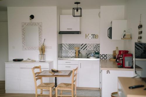 une cuisine avec des armoires blanches et une table et des chaises dans l'établissement Chez Malo, à Perros-Guirec
