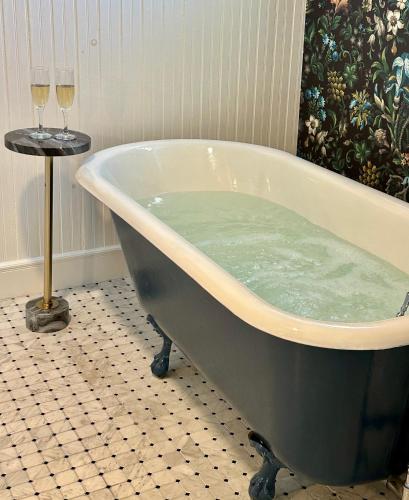 a bath tub in a bathroom with two glasses of wine at North Hero House Inn and Resort in North Hero
