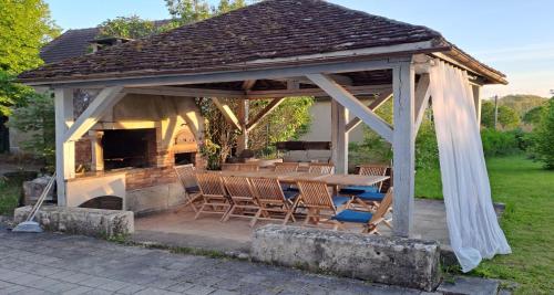a wooden gazebo with a table and chairs at Domaine des Tilleuls - Grand Jardin avec Piscine privée sur le Canal de Bourgogne in Ravières