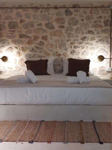 a large bed in a room with a stone wall at Villa Plaka 16 - 'The Cave' - Drepano, Nafplio in Drepana