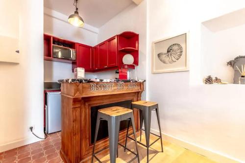 une cuisine avec des placards rouges et un comptoir avec des tabourets dans l'établissement La Ponche l Beachside l Shellter Rentals, à Saint-Tropez