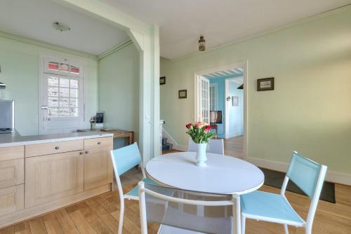 une cuisine avec une table blanche et des chaises bleues dans l'établissement Villa La Petite Normandy Vue Mer, à Trouville-sur-Mer