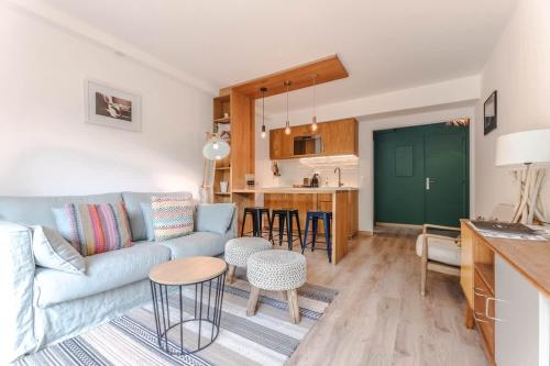 un salon avec un canapé et une cuisine dans l'établissement Le Bailly l Beachside & Rooftop l Shellter Rentals, à Saint-Tropez