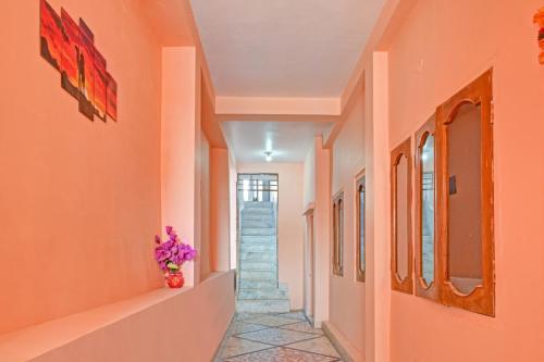 GuwārighātHotel O Maa Narmada的走廊上设有橙色墙壁和紫色花瓶