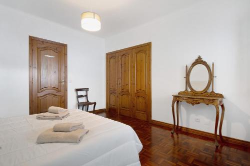 a bedroom with a bed with a mirror and a chair at Pascoal House in Ribeira Grande