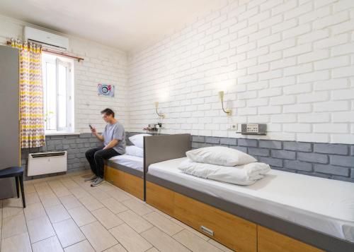a man sitting on a bed in a room at ololoFreelander Hostel&Coworking in Bishkek