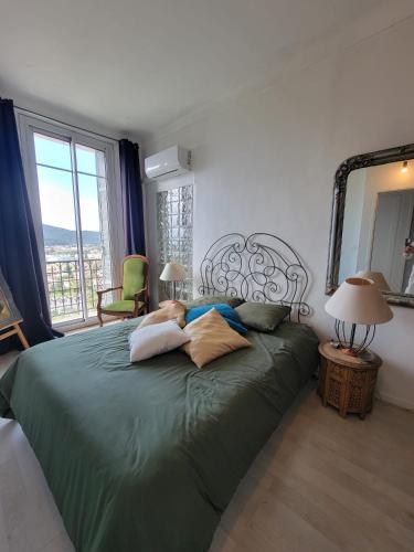 - une chambre avec un lit vert et une grande fenêtre dans l'établissement Les îles d'or, à Hyères