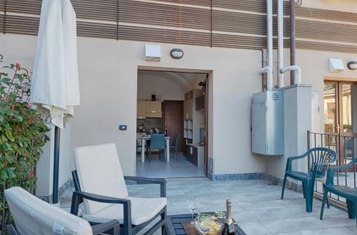 a patio with chairs and an umbrella and a table at LakeView LakeComo, CIPRESSO 2, 4Seasons, Terrace, 30m to Lake! by STAYHERE-LAKECOMO in Acquaseria