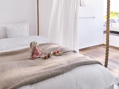 a stuffed teddy bear sitting on a bed at Grecotel LUXME White in Adelianos Kampos