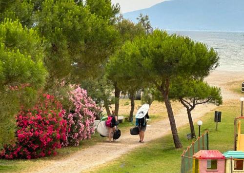a person walking down a path with a surfboard at Residence Talamone Il Poderino in Talamone